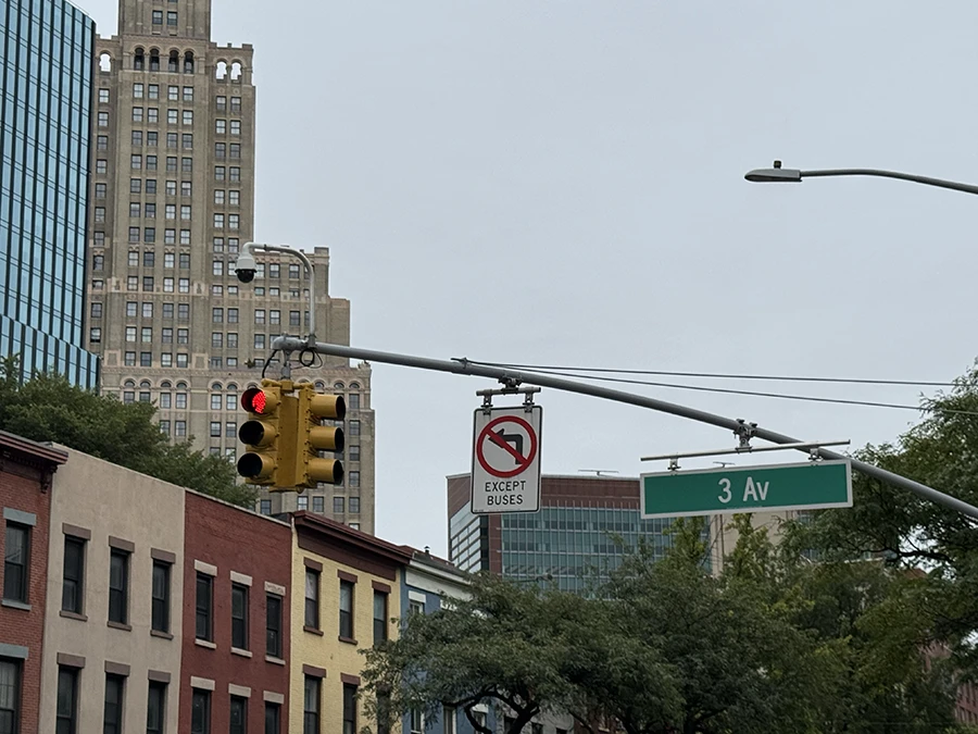 Photo of a traffic camera on top of a traffic light.
