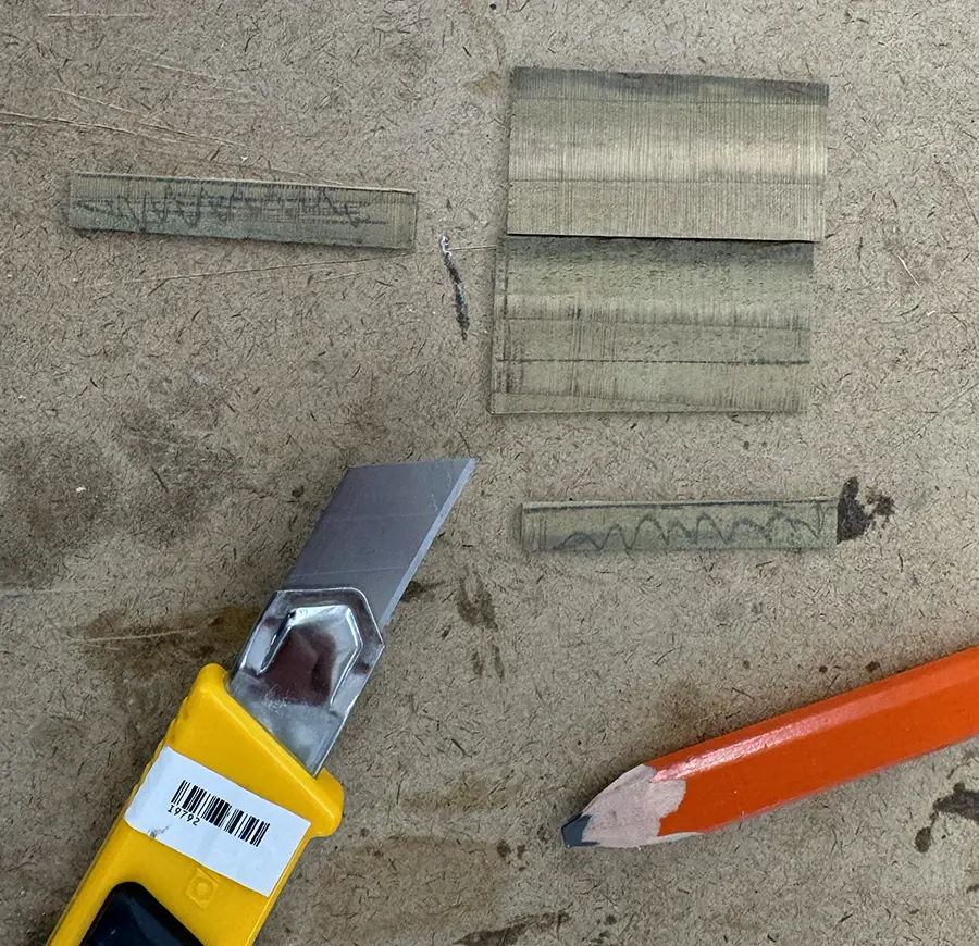 Small wooden planks and a box cutter on top of a table.