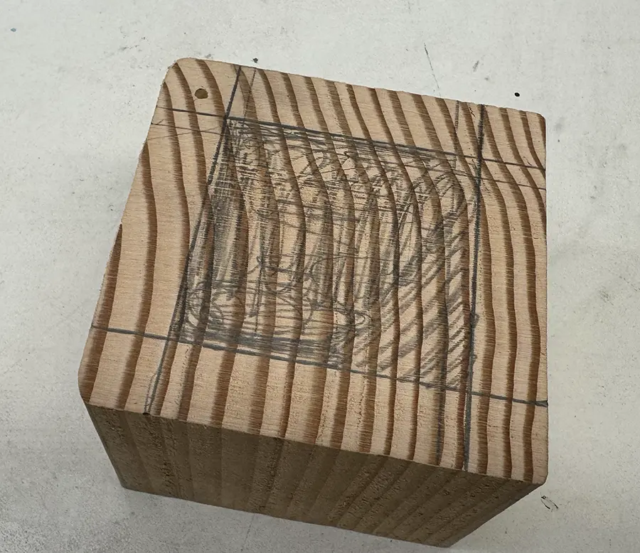 Wooden cube with an inset square-shaped pencil marking.