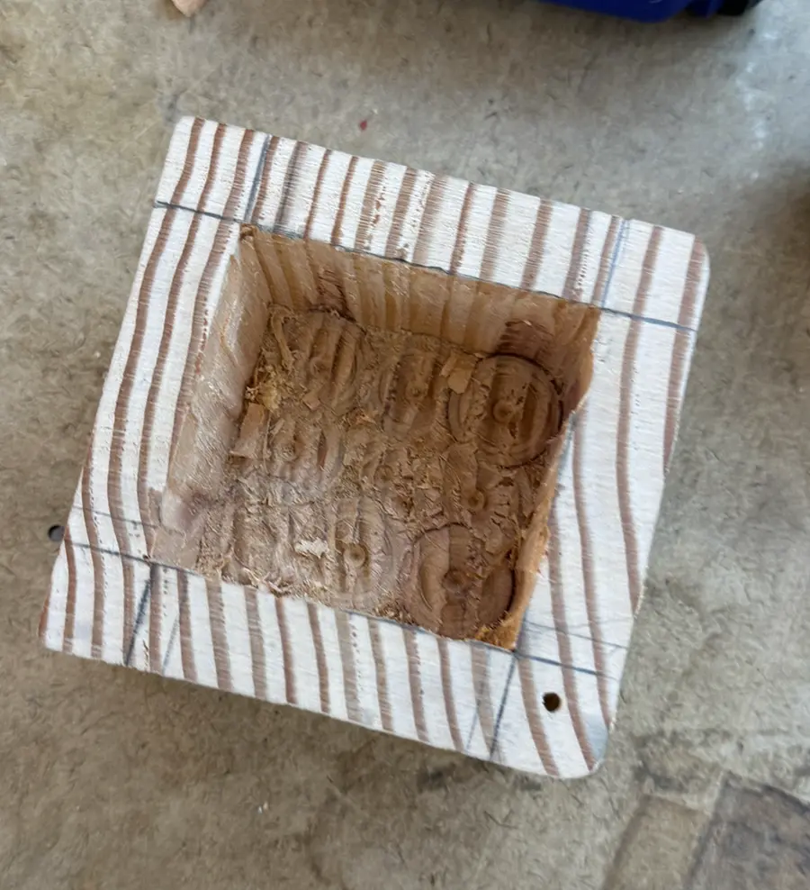 Wooden cube with a squared out cavity inside it. Top view.