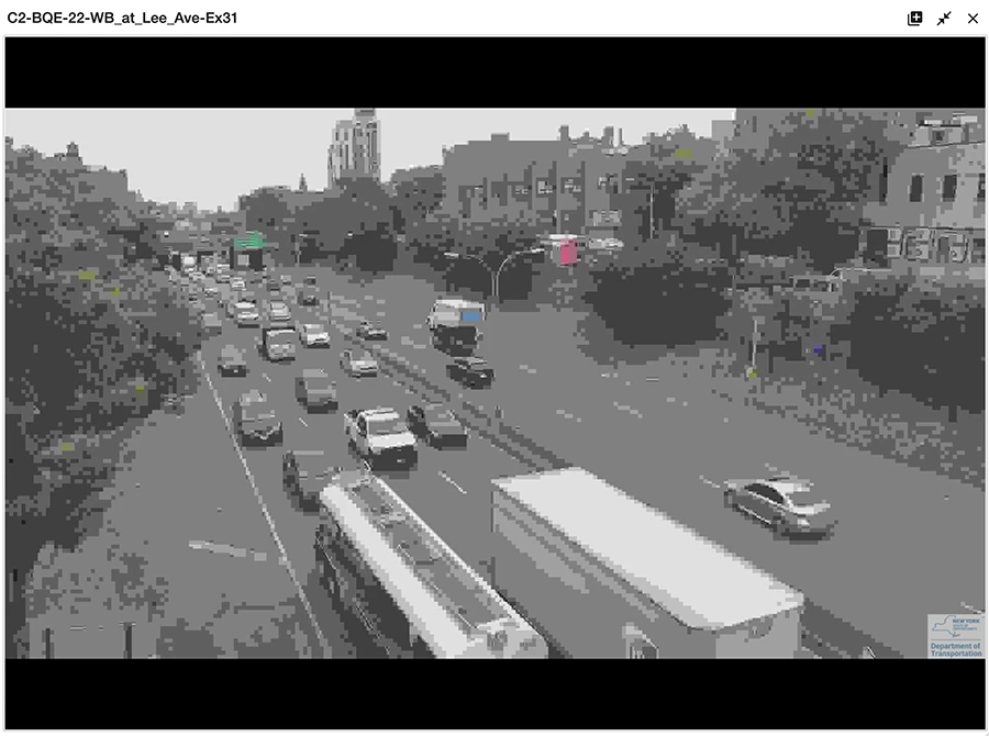 Photo of a city street, with a very low resolution and in black and white, except for some pixels with color.