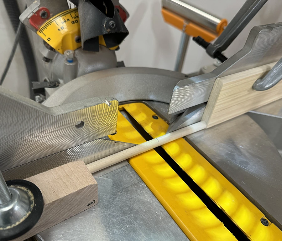 A block clamped on the compound miter saw and a small dowel ready to be cut.