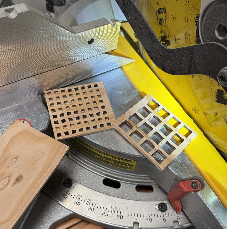 Two wooden pieces with square grids on the miter saw.