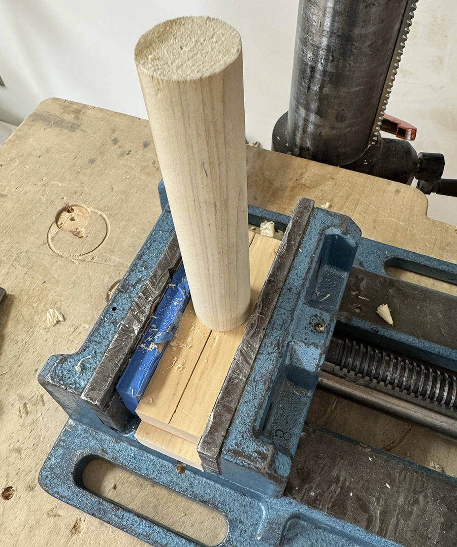 Long dowel being held by vise.