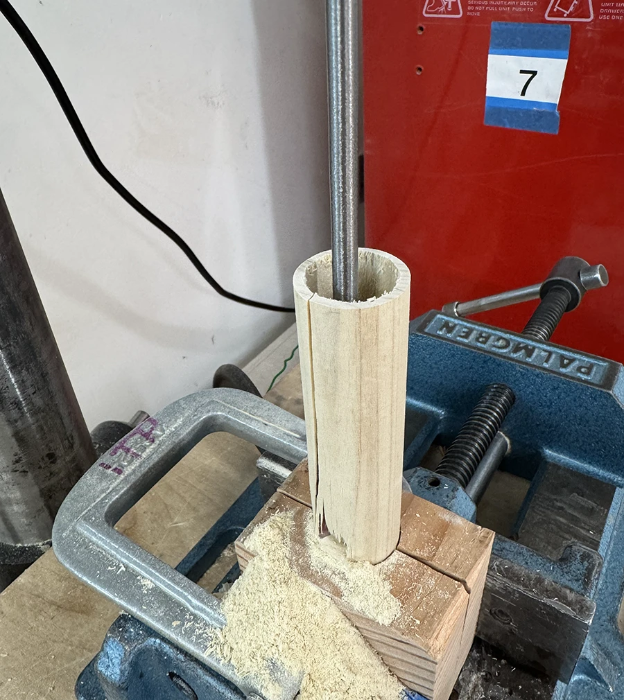 Dowel with a lengthwise hole and a crack down the side with a tear at the bottom.