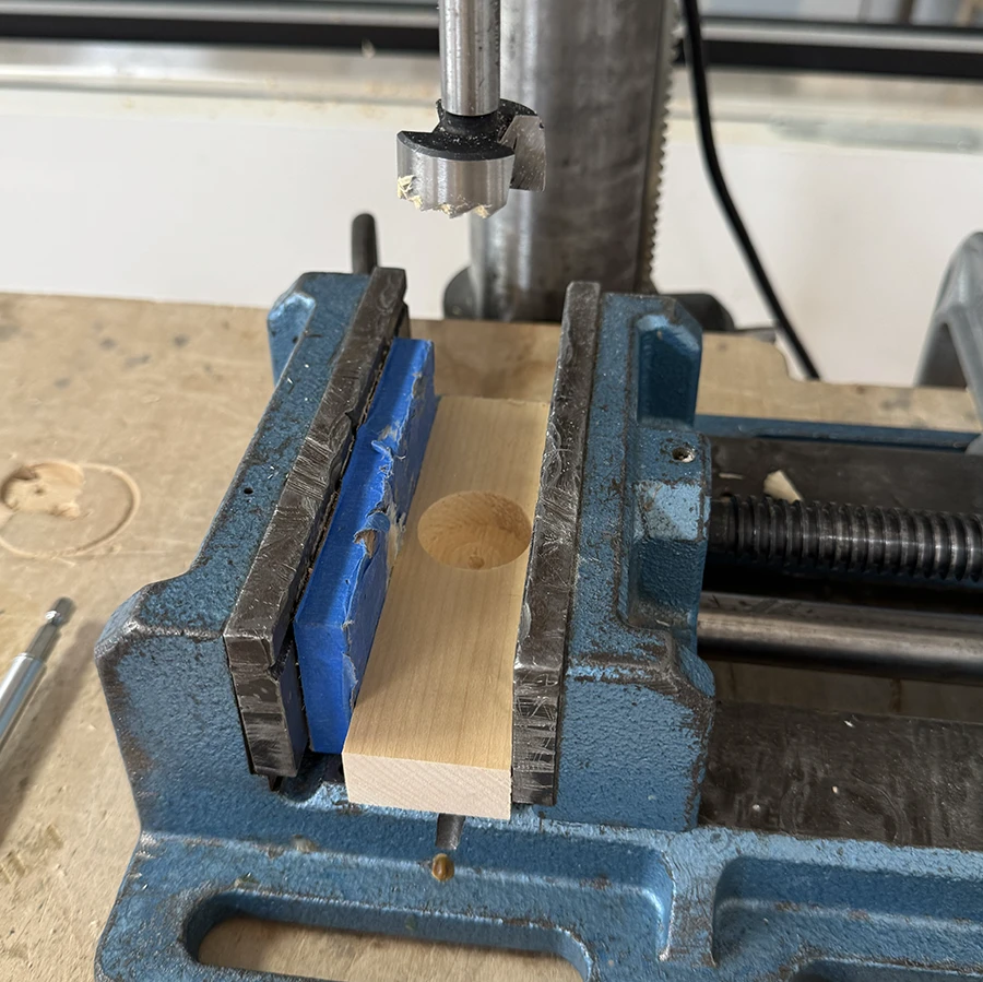 Piece of wood with a large circle drilled out of it.