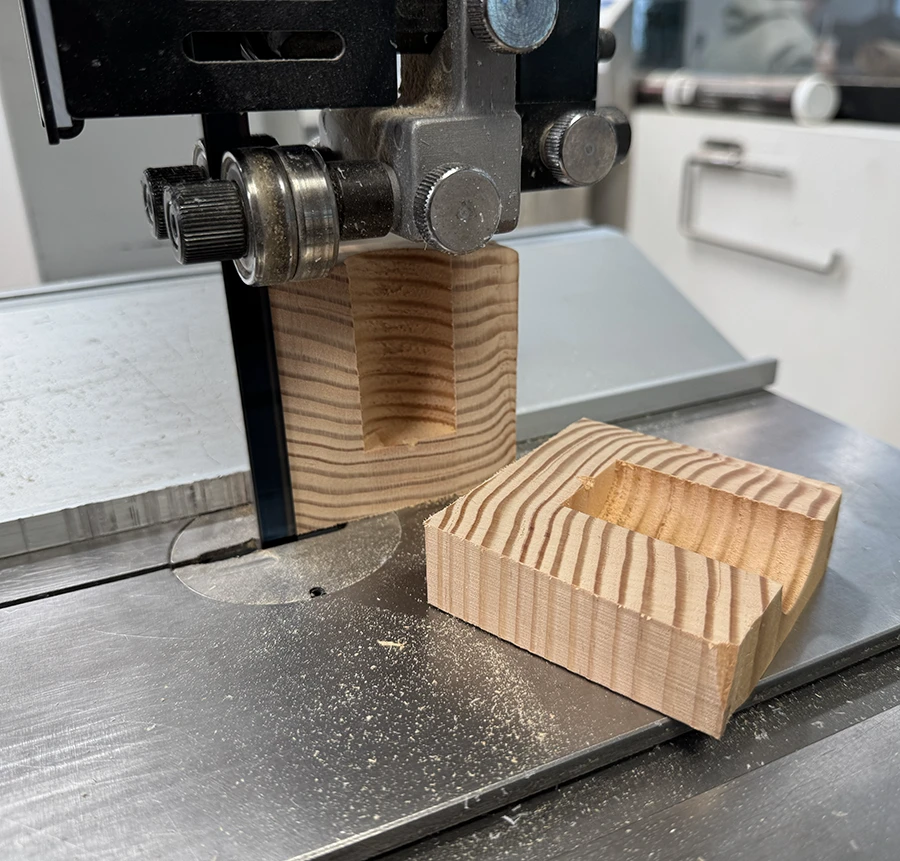 A block of wood with a hole in the center, cut lengthwise to expose both sides of the hole.