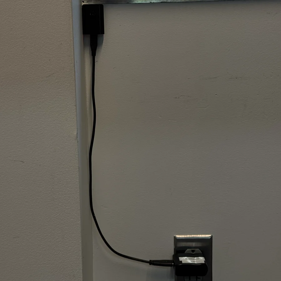 Small camera mounted on a corner of a wall, with a cable coming out to a nearby wall outlet.