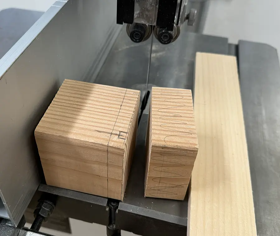 A block of wood being cut in the band saw.