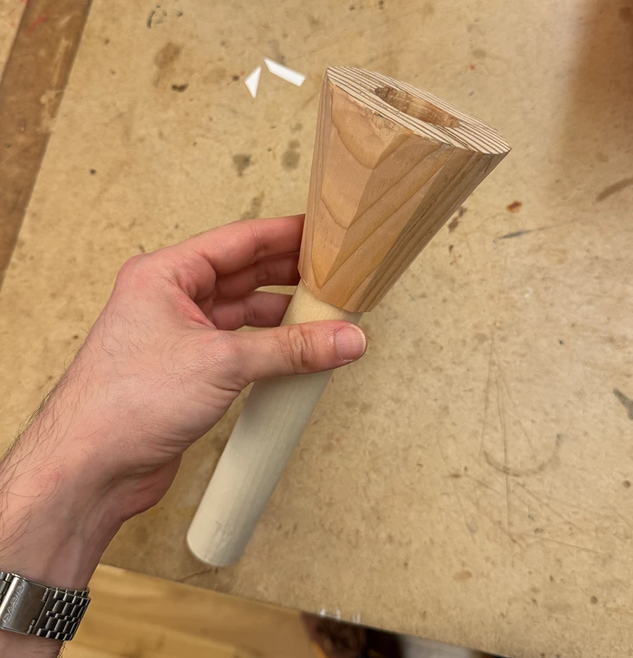 A conic decagonal prism with a wooden dowel coming out of it.