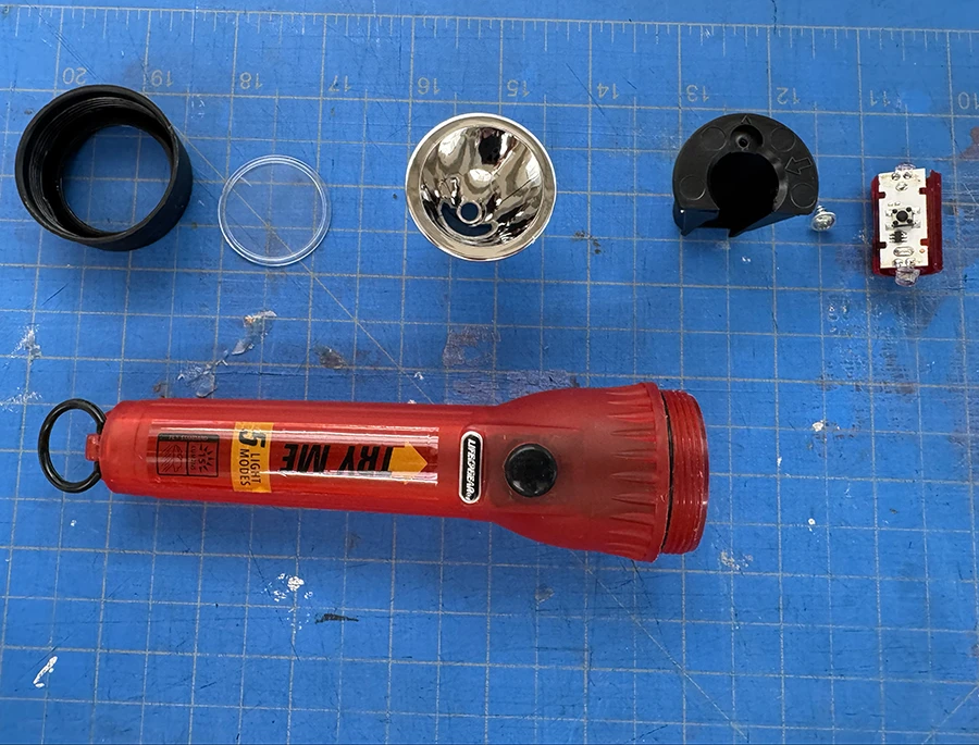 Flashlight pieces on a cutting mat.