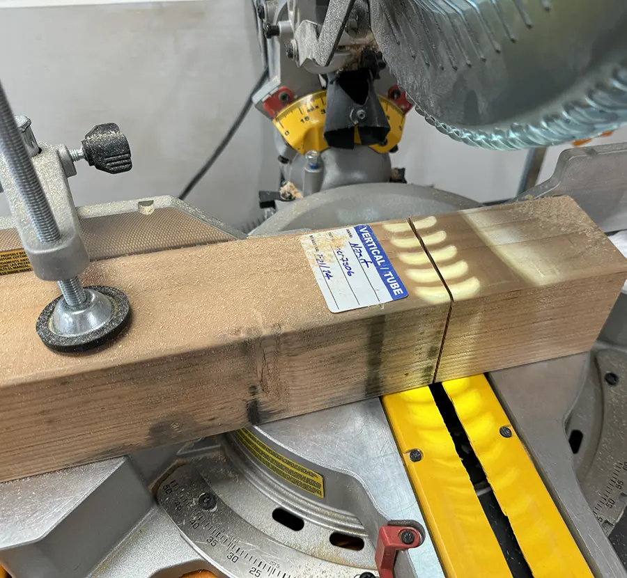 Block of wood being cut on the compound miter saw.