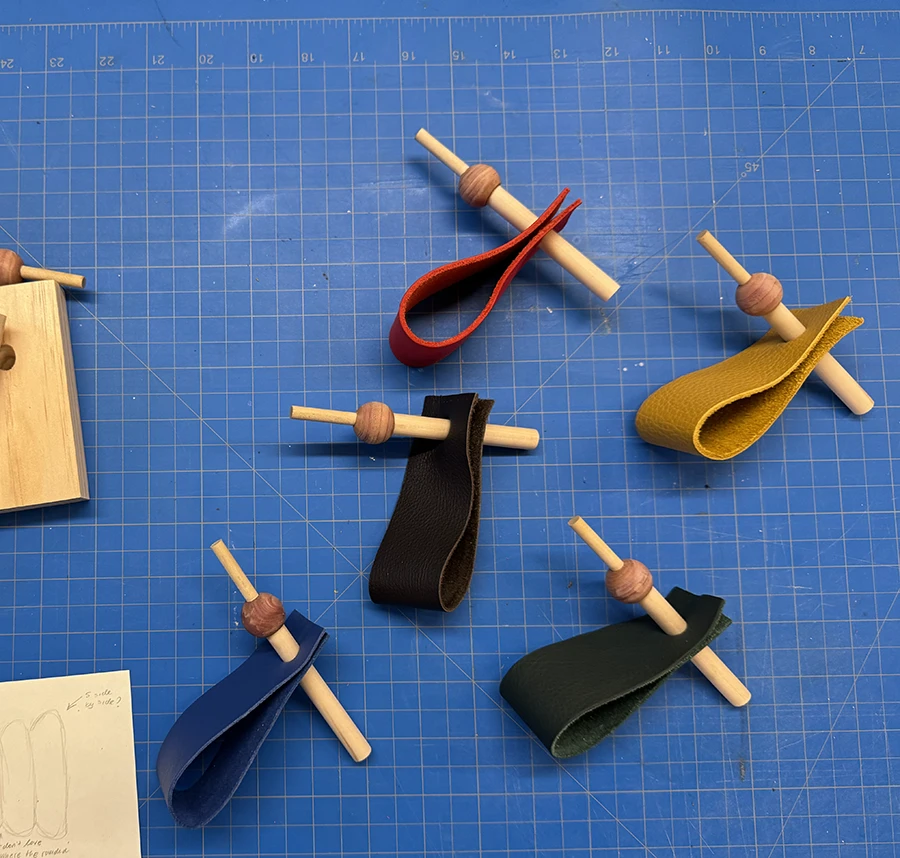 5 dowels, each going through a wooden sphere and a leather strap on two ends.