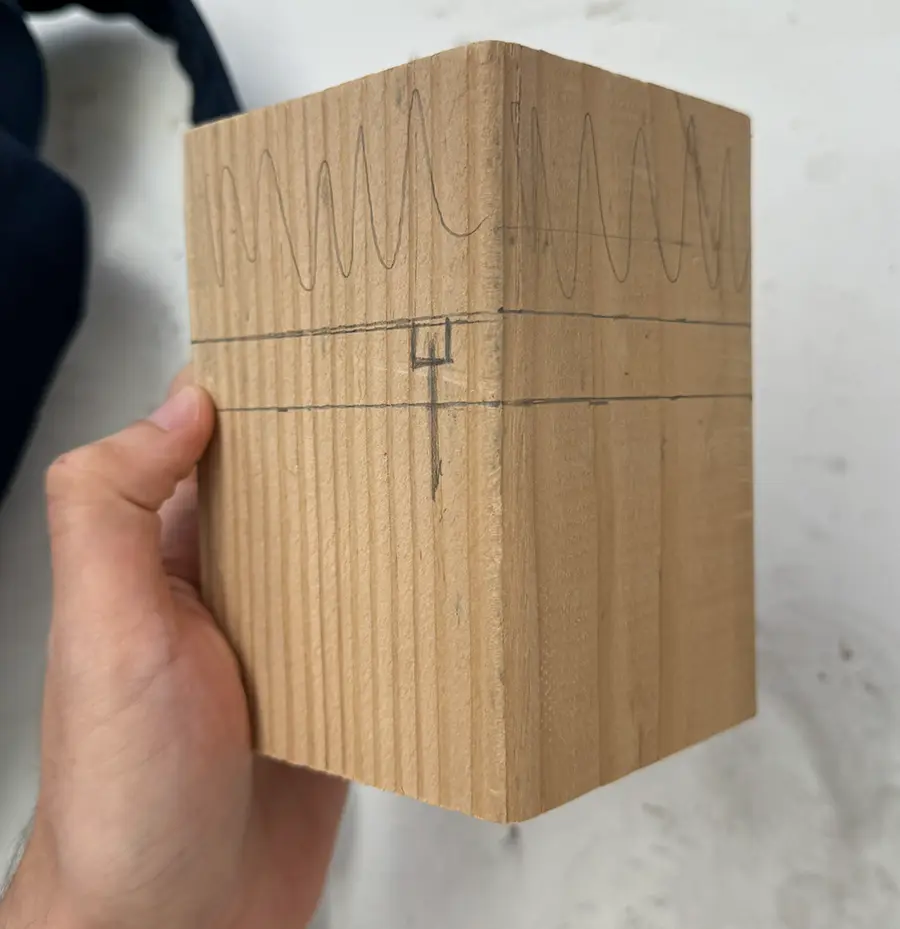 A block of wood with lines and markings made with a pencil.