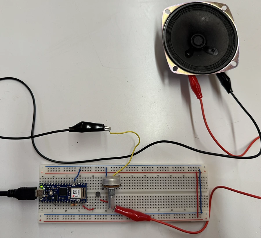 A breadboard with an arduino nano 33 iot, a potentiometer, a pnp transistor and an 8ohm speaker.
