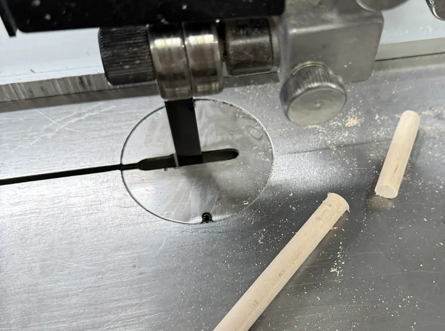 Wooden dowel being cut on the band saw.