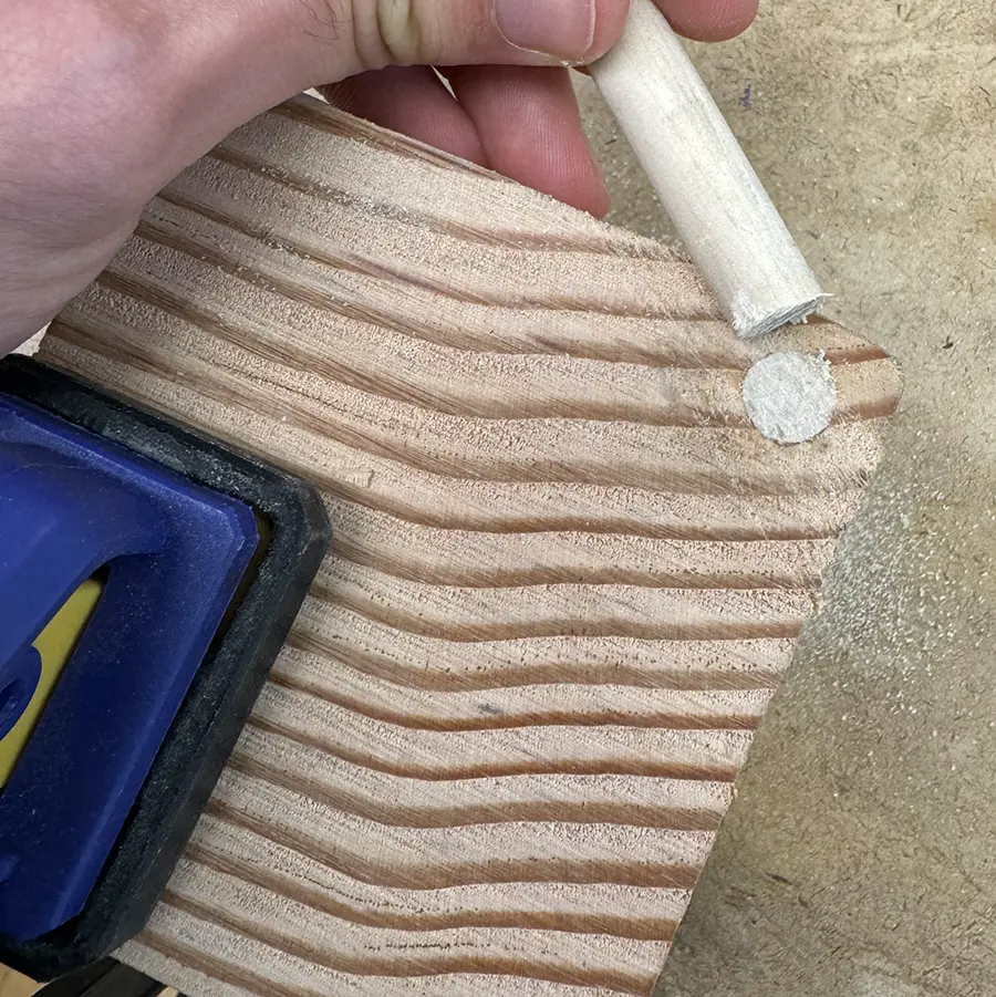 Wooden dowel insed a wood plank, cut flush with the plank.