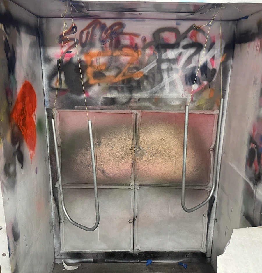 Two bent metal tubes hanging from the paint booth.