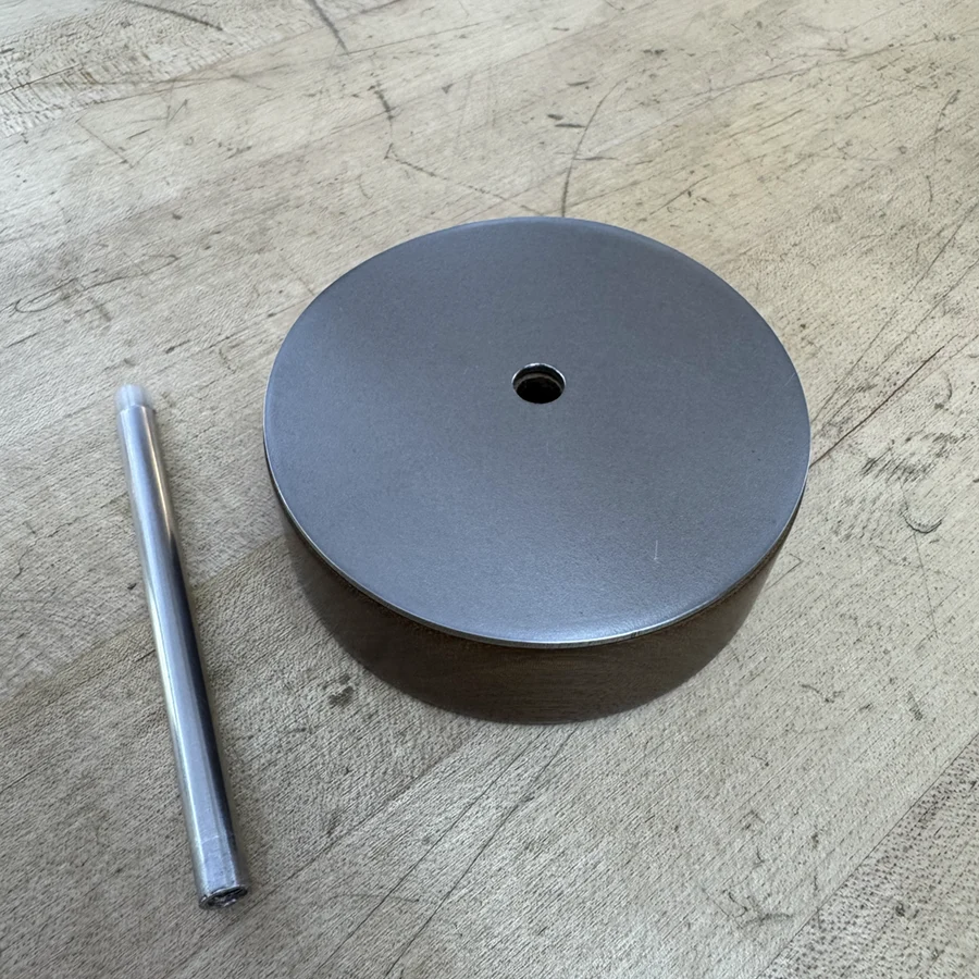 Metal tube and round wooden piece with metal plate on top.