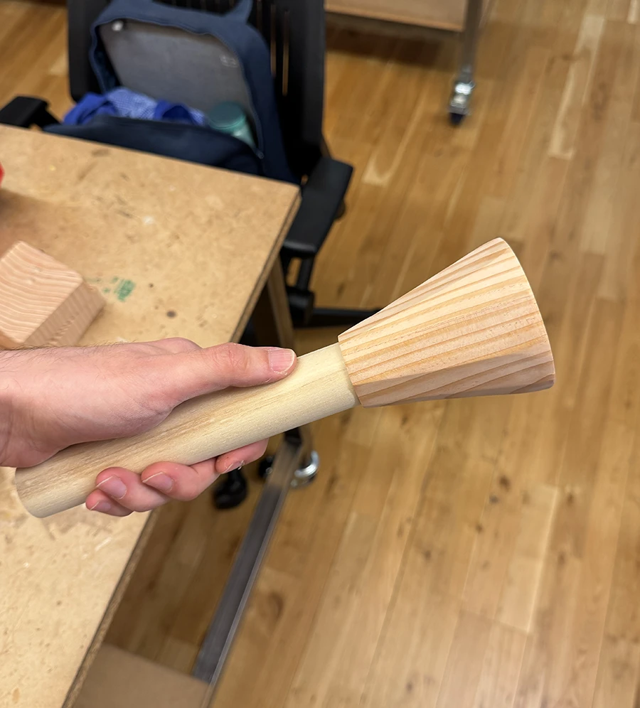 A conic decagonal prism with a wooden dowel coming out of it.