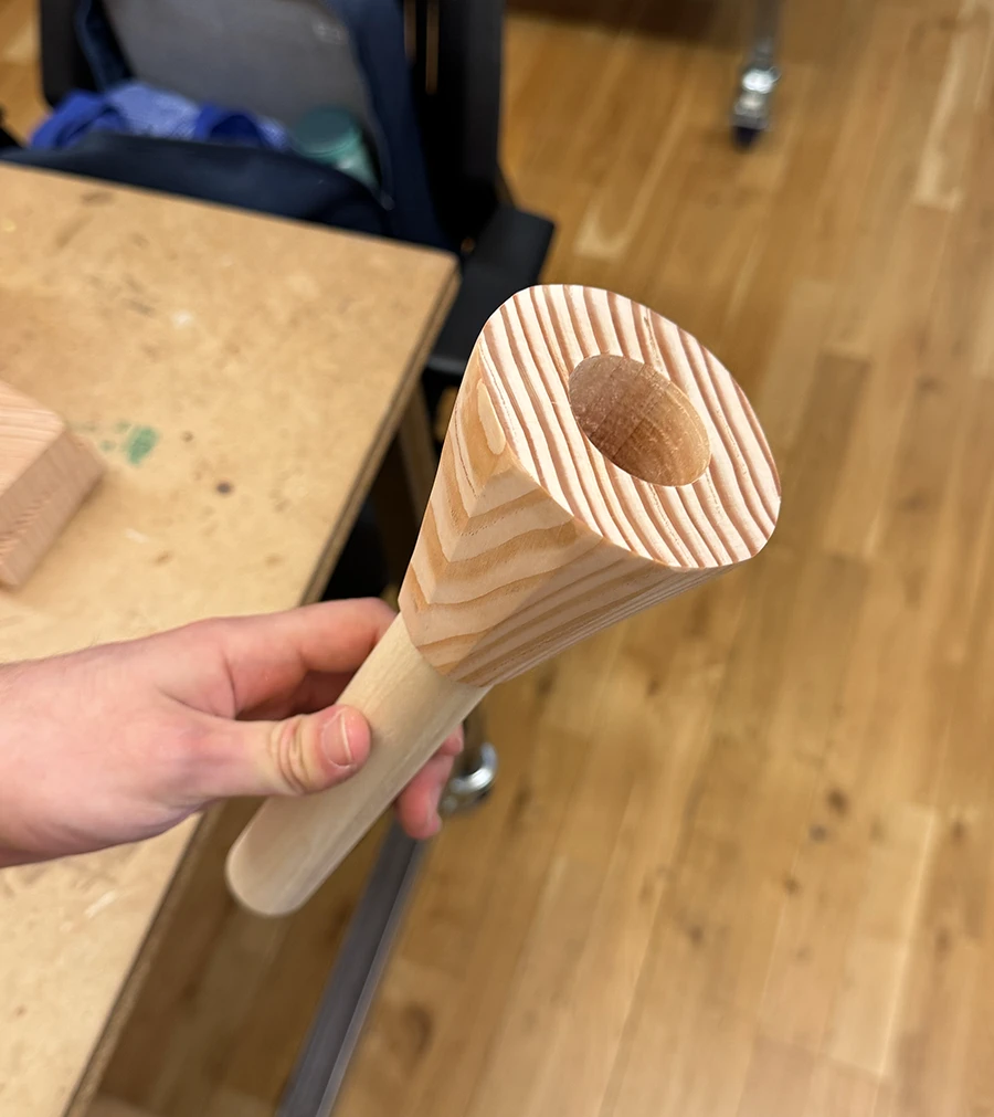 A conic decagonal prism with a wooden dowel coming out of it.