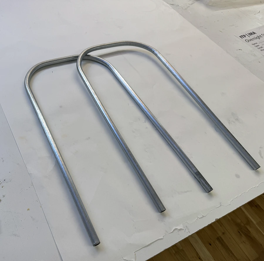 Two bent metal tubes on a piece of white paper