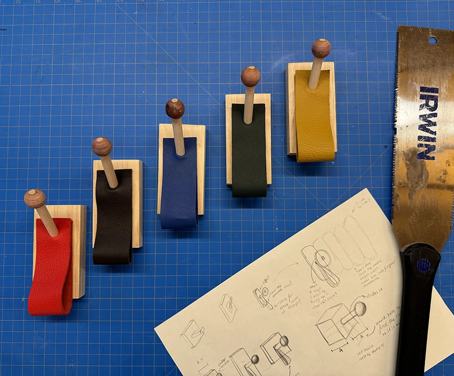 5 wooden hangers on a blue cutting mat, with a saw next to them.