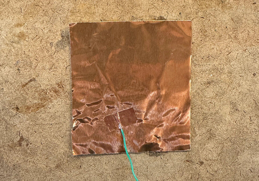 A copper plate with a wire on top of it, connected with a small strip of copper tape.