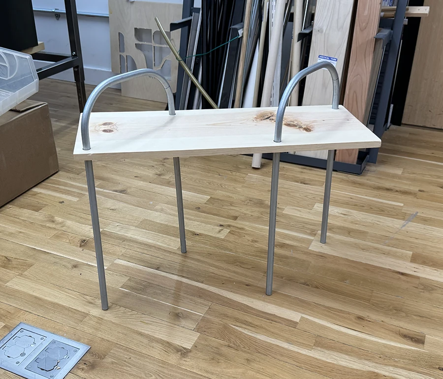 Metal table legs going through a wooden plank.