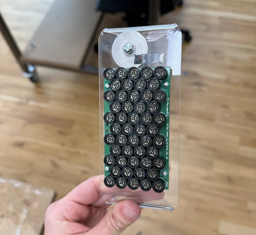Parametric speaker and webcam mounted on a piece of bent acrylic.