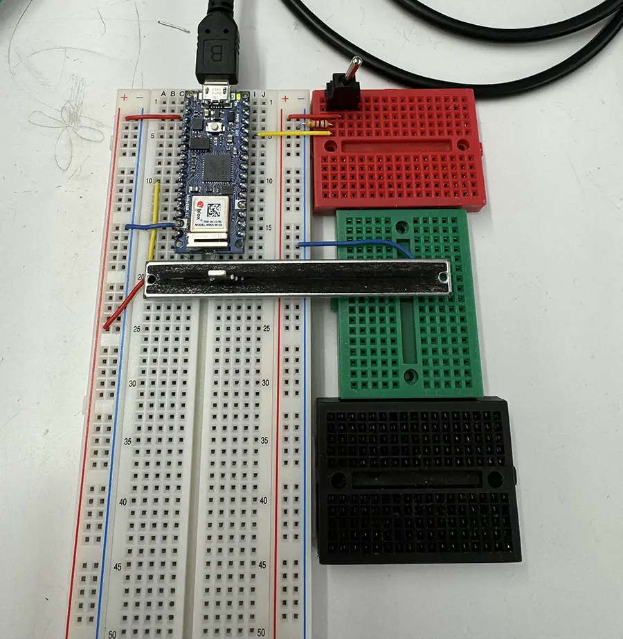 Three breadboards side by side with an arduino nano, one slider potentiometer set horizontally and one switch on the top right.