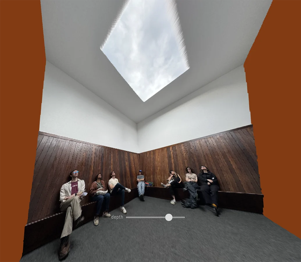 People sitting down in a room looking at a rectangular opening in the ceiling.