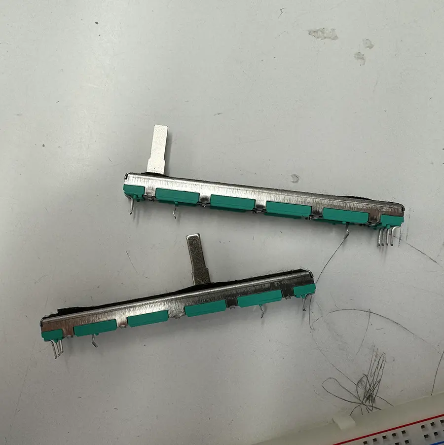 Two slider potentiometers on top of a table.