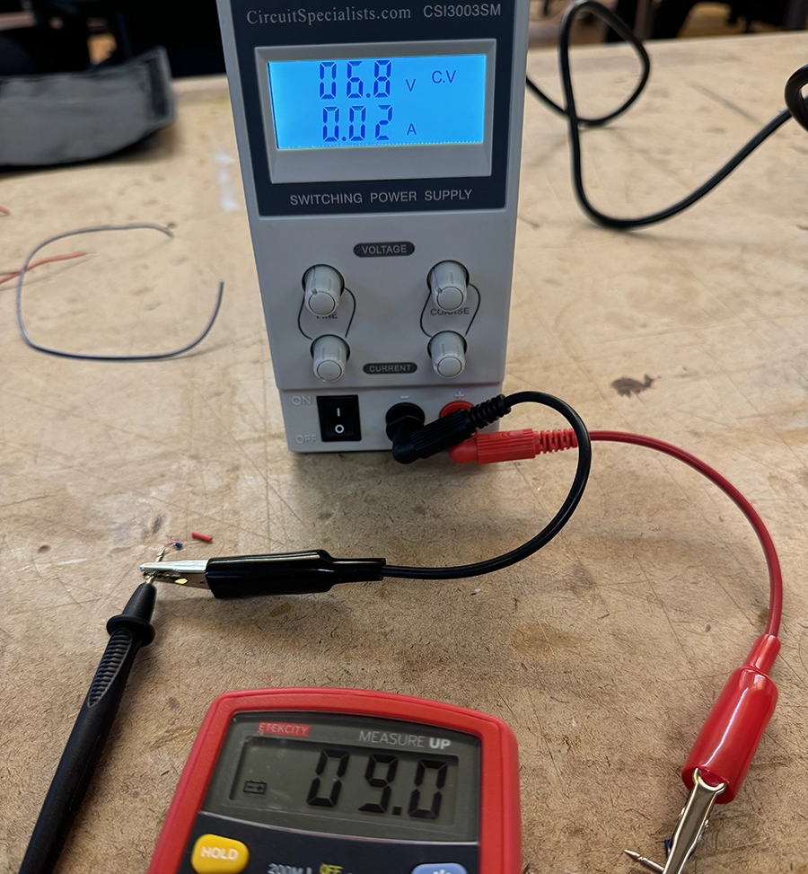 Variable power supply reads 6.8V, 0.02A. The leads are connected to a multimeter in voltage reading mode. It reads 9.0V.